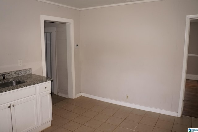 kitchen with sink, dark stone counters, white cabinets, and light tile patterned floors