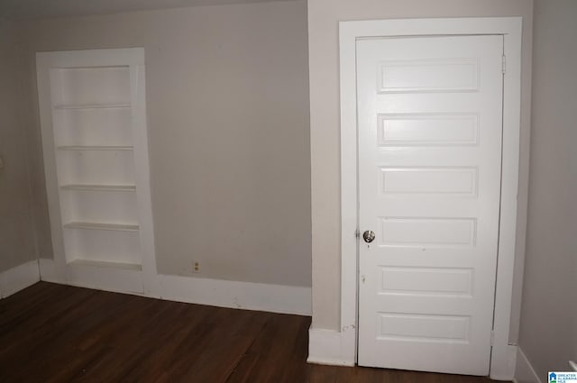 spare room featuring dark wood-type flooring and built in features