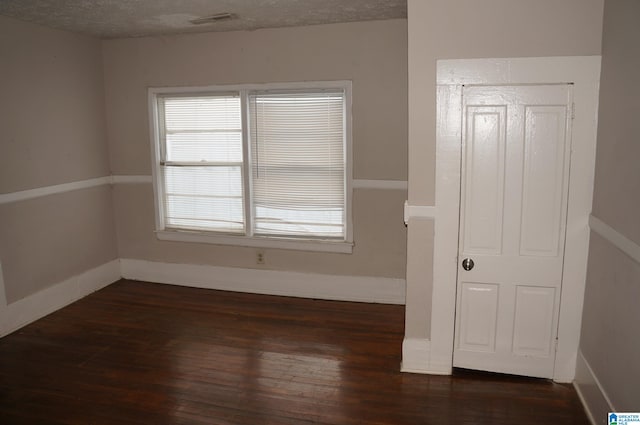 spare room with a textured ceiling and dark hardwood / wood-style floors