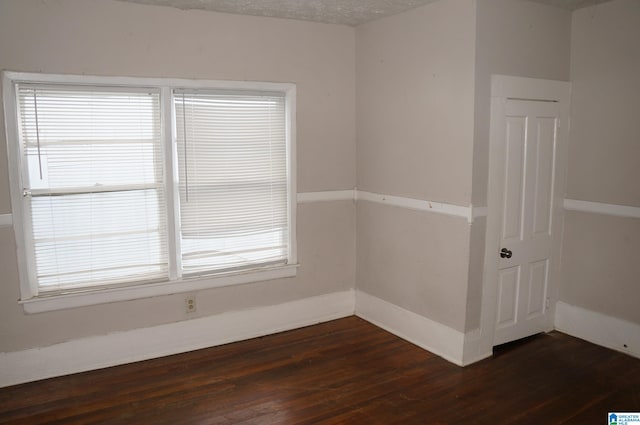 empty room featuring dark hardwood / wood-style flooring and a textured ceiling