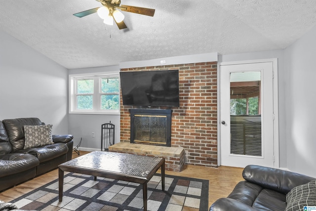 living room featuring lofted ceiling, a fireplace, light hardwood / wood-style floors, and a textured ceiling