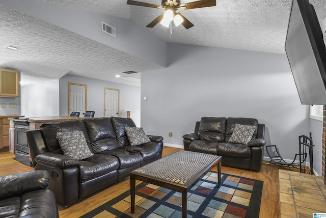 living room featuring ceiling fan, vaulted ceiling, a textured ceiling, and light wood-type flooring