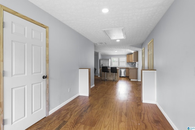 corridor with hardwood / wood-style floors and a textured ceiling