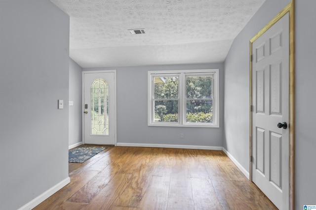 entryway with hardwood / wood-style flooring, vaulted ceiling, and a textured ceiling