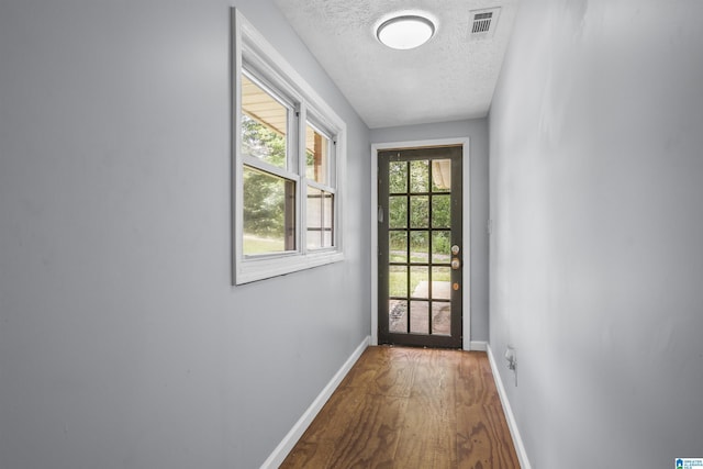 doorway to outside featuring wood-type flooring and a textured ceiling