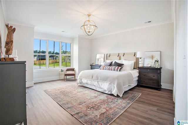 bedroom with baseboards, wood finished floors, visible vents, and an inviting chandelier