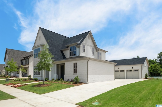 modern farmhouse with board and batten siding, a front yard, brick siding, and a garage