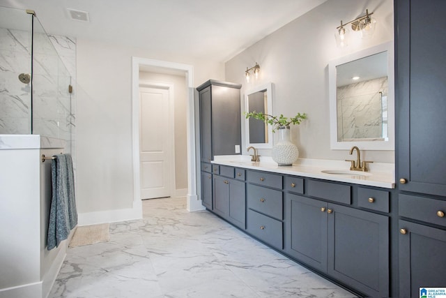 full bath featuring marble finish floor, double vanity, a sink, and baseboards