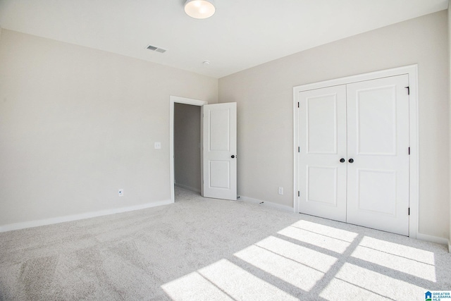 unfurnished bedroom featuring baseboards, visible vents, a closet, and light colored carpet