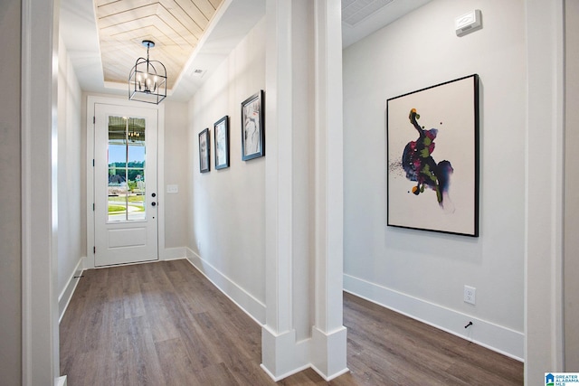 entryway with visible vents, baseboards, wood finished floors, an inviting chandelier, and a tray ceiling