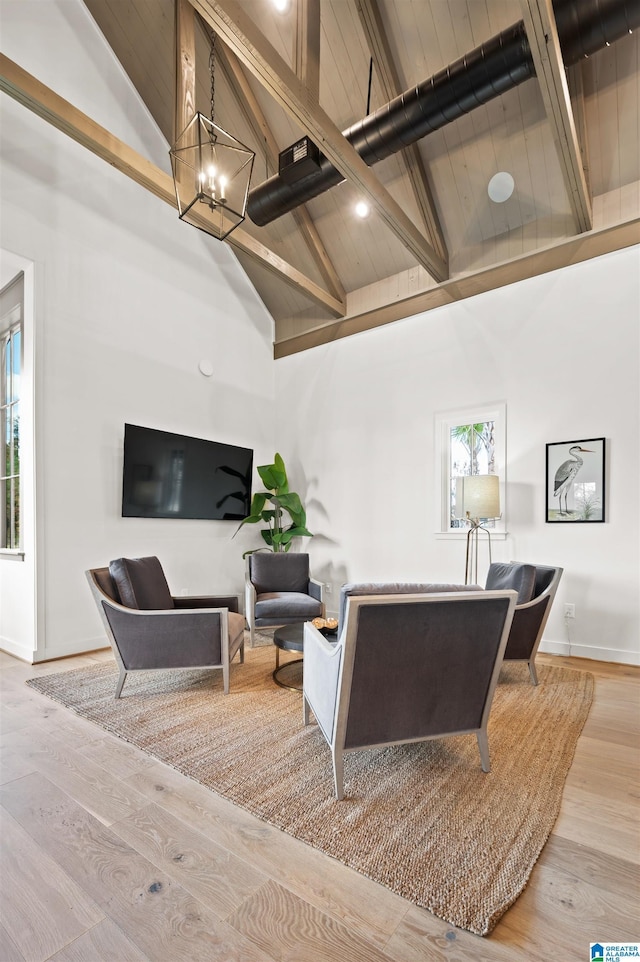 living area featuring high vaulted ceiling, wood finished floors, baseboards, beamed ceiling, and an inviting chandelier