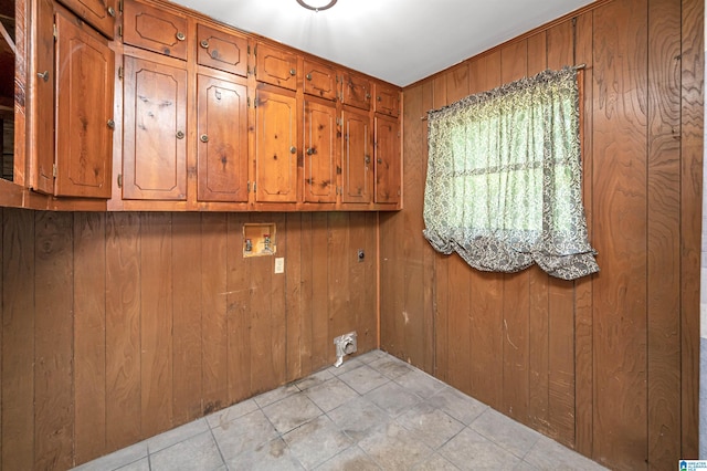 clothes washing area featuring wood walls, cabinets, and washer hookup