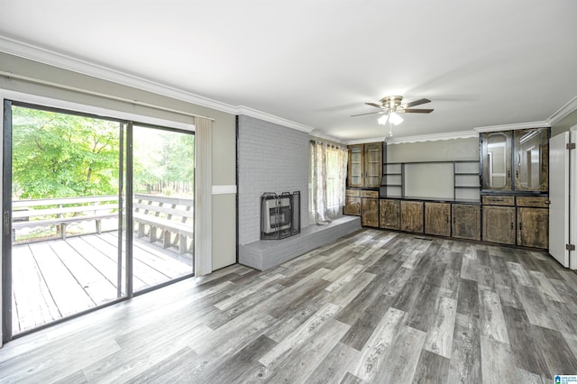 unfurnished living room with a brick fireplace, hardwood / wood-style flooring, ornamental molding, and ceiling fan