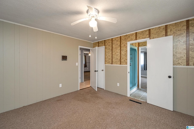 unfurnished bedroom featuring a textured ceiling, ceiling fan, crown molding, and light carpet