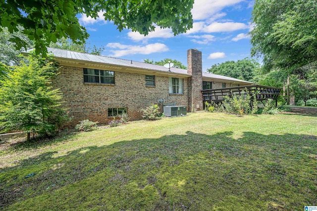 back of property featuring a wooden deck, cooling unit, and a lawn