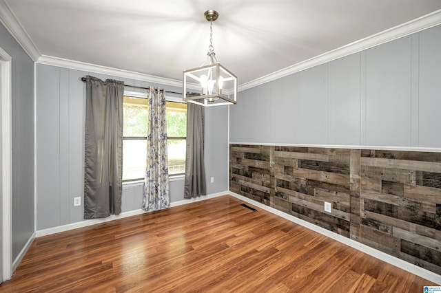 empty room featuring hardwood / wood-style flooring, an inviting chandelier, and ornamental molding