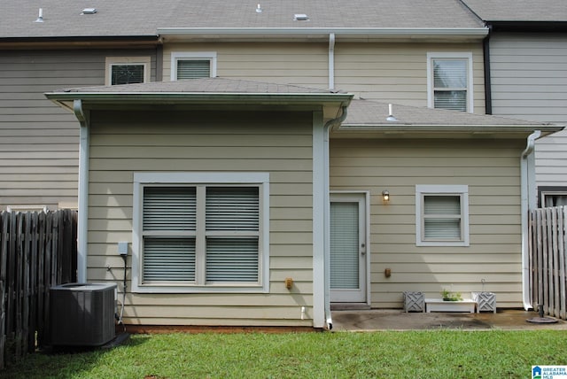 rear view of house with cooling unit and a yard