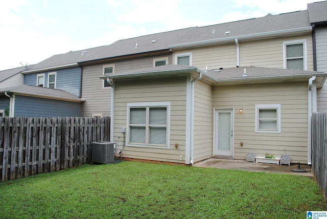 rear view of property with central air condition unit and a yard