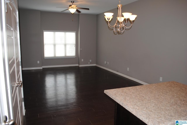 spare room featuring ceiling fan with notable chandelier and dark wood-type flooring