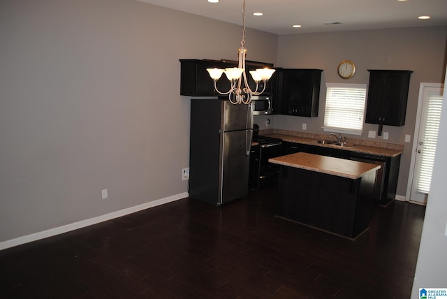 kitchen with appliances with stainless steel finishes, a chandelier, hanging light fixtures, sink, and a kitchen island