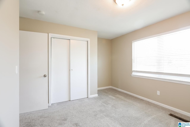 unfurnished bedroom featuring a closet and light colored carpet