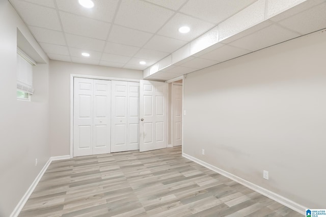 unfurnished bedroom featuring a paneled ceiling, light wood-type flooring, and a closet