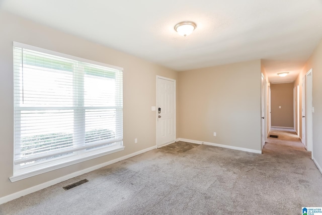 spare room featuring light colored carpet and a wealth of natural light