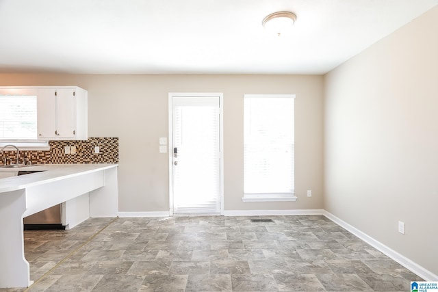 kitchen with tasteful backsplash, white cabinetry, and sink