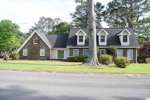 cape cod home with brick siding and a front lawn