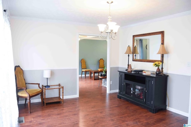 sitting room with an inviting chandelier, baseboards, ornamental molding, and dark wood-type flooring