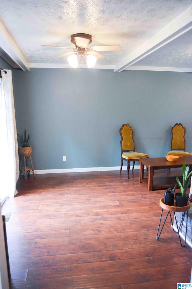 living area with crown molding, baseboards, a textured ceiling, and wood finished floors