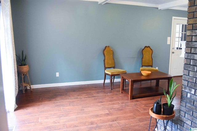 living area featuring crown molding, beam ceiling, baseboards, and wood finished floors