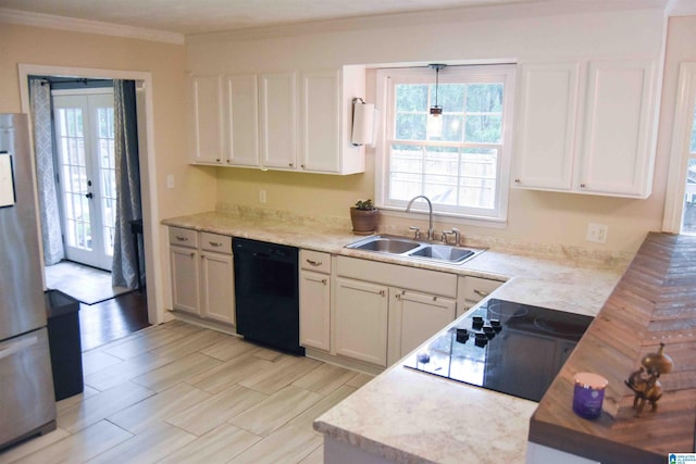 kitchen with light countertops, black appliances, a sink, and white cabinetry