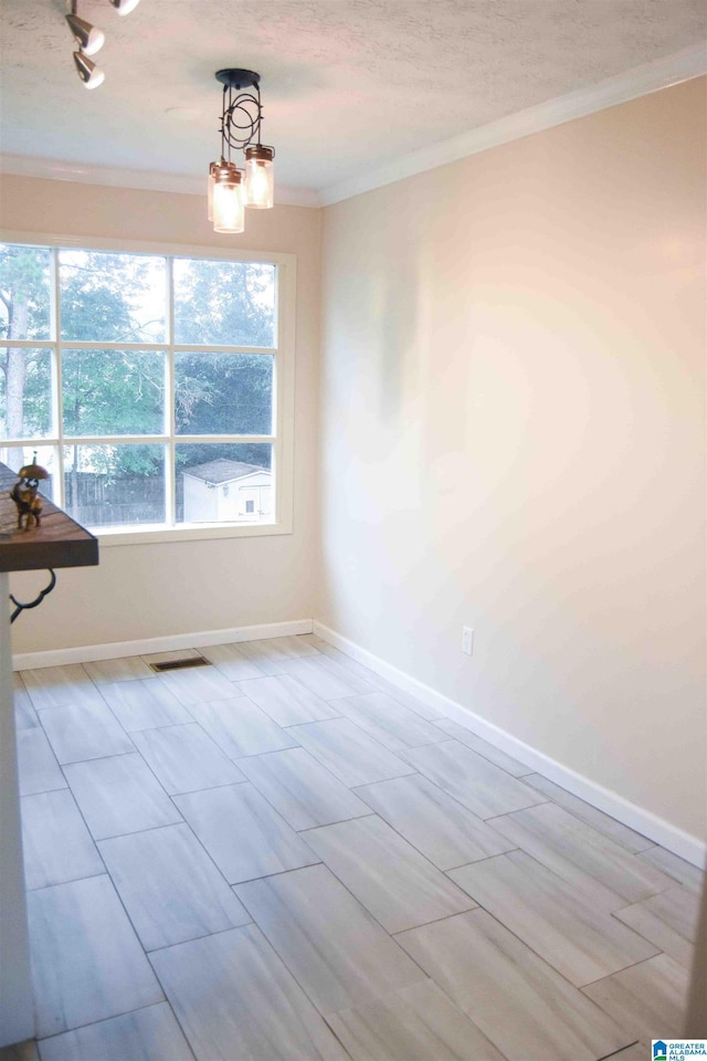 empty room with ornamental molding, visible vents, a textured ceiling, and baseboards