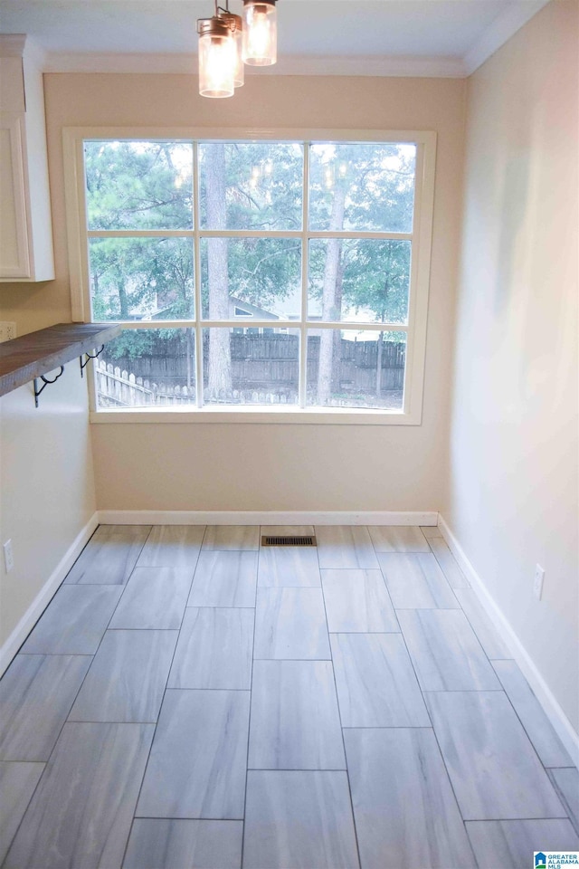 unfurnished dining area featuring visible vents, ornamental molding, and baseboards