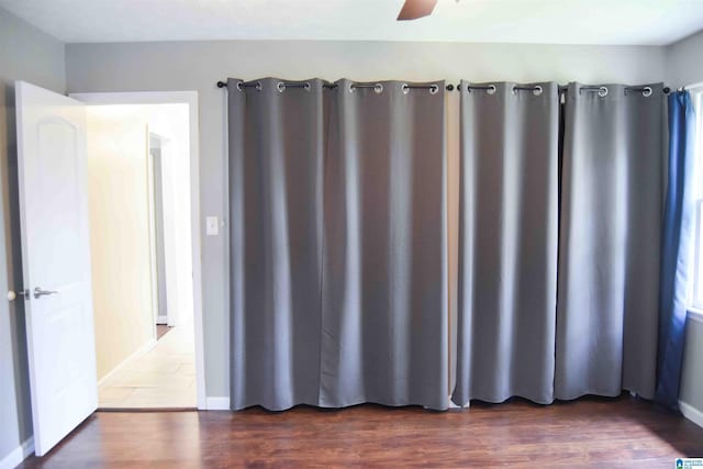 empty room with baseboards and dark wood-type flooring