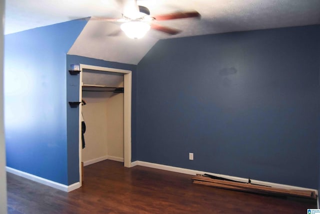 unfurnished bedroom with dark wood finished floors, lofted ceiling, a closet, a ceiling fan, and baseboards