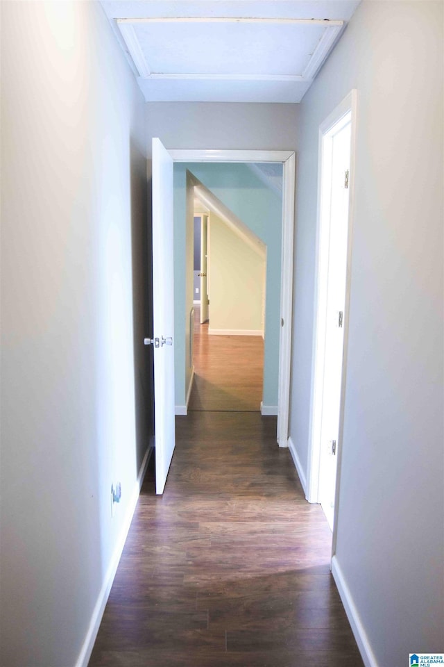 corridor featuring attic access, dark wood finished floors, and baseboards