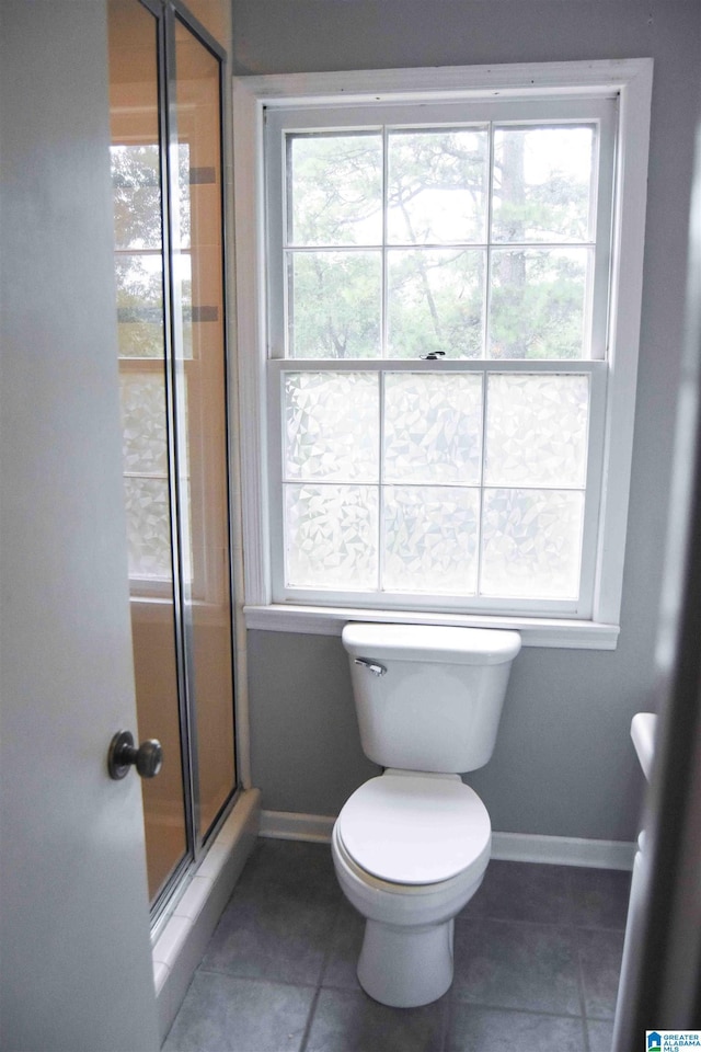 bathroom featuring a shower stall, baseboards, tile patterned floors, and a healthy amount of sunlight