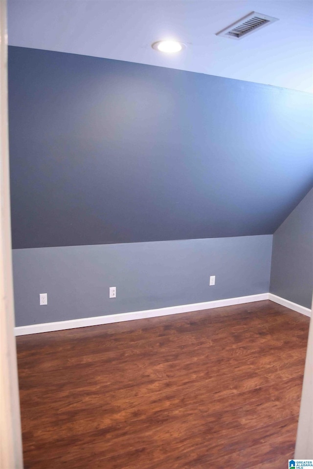 bonus room with dark wood-type flooring, visible vents, vaulted ceiling, and baseboards