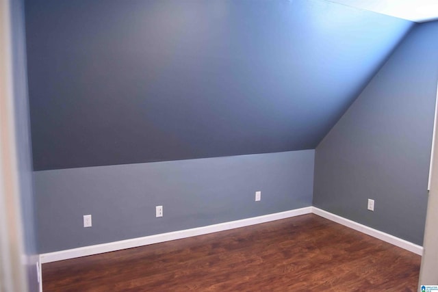 additional living space featuring lofted ceiling, dark wood-type flooring, and baseboards