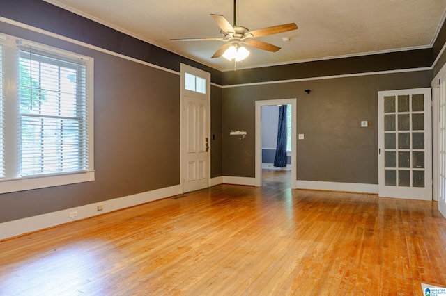 empty room featuring ceiling fan, light wood-type flooring, and crown molding