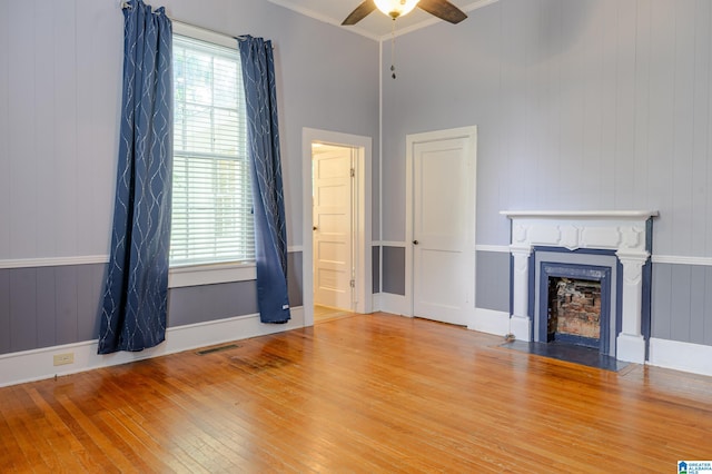 unfurnished living room featuring light hardwood / wood-style floors, ceiling fan, and crown molding