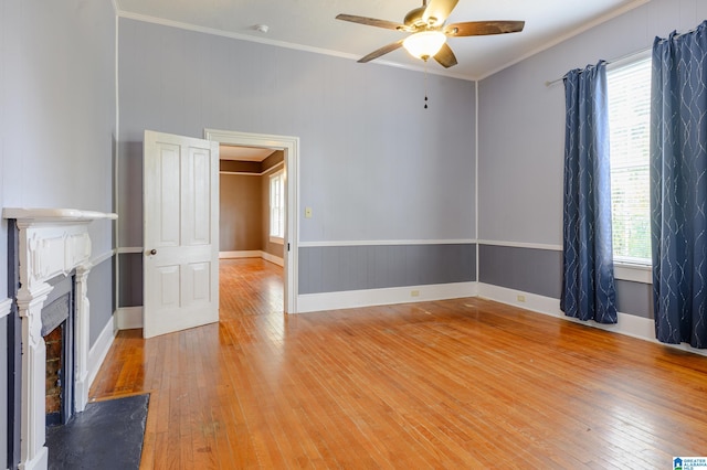 unfurnished living room featuring ceiling fan, plenty of natural light, light wood-type flooring, and ornamental molding