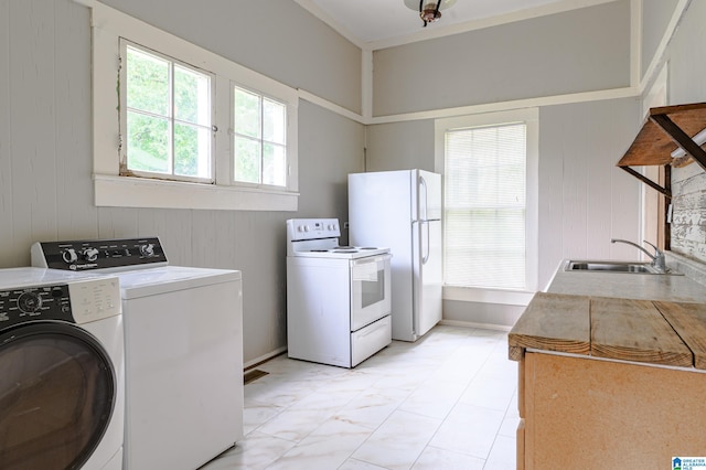 clothes washing area featuring washing machine and clothes dryer, wooden walls, and sink