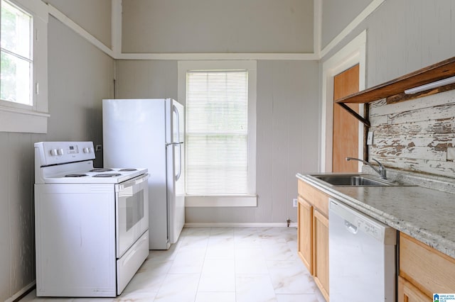 kitchen with light brown cabinets, white appliances, sink, and wooden walls