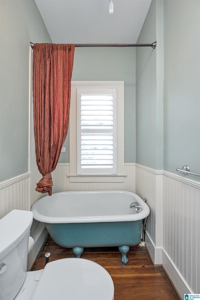 bathroom featuring a bath, hardwood / wood-style flooring, and toilet