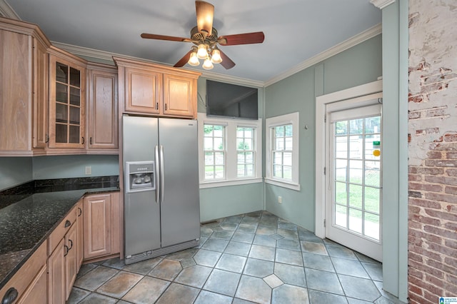 kitchen with ornamental molding, a healthy amount of sunlight, stainless steel fridge, and dark stone countertops