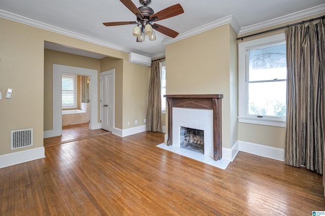 unfurnished living room with a tile fireplace, hardwood / wood-style floors, a wall mounted AC, ornamental molding, and ceiling fan