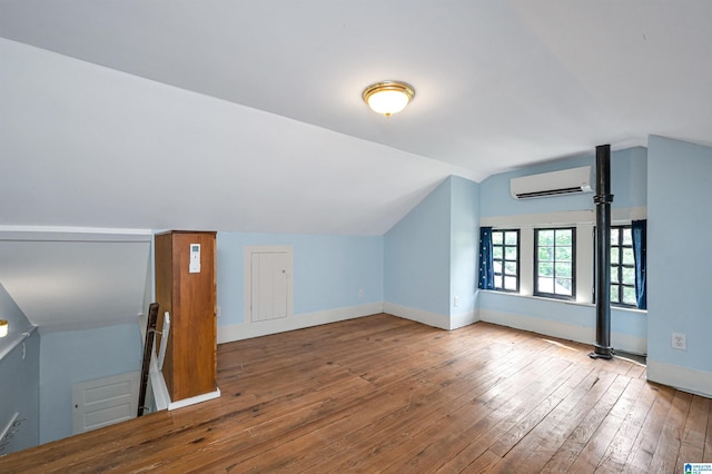 additional living space with vaulted ceiling, hardwood / wood-style floors, and a wall unit AC